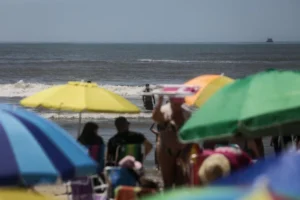 Com calor de 33°C e bandeira verde, veranistas lotam faixa de areia na praia de Tramandaí