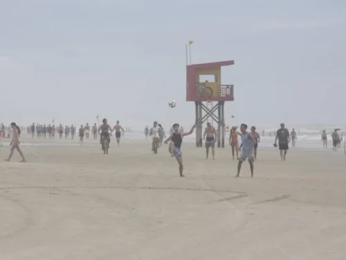 Veranistas aproveitam céu nublado para caminhadas e jogos na beira da praia de Atlântida