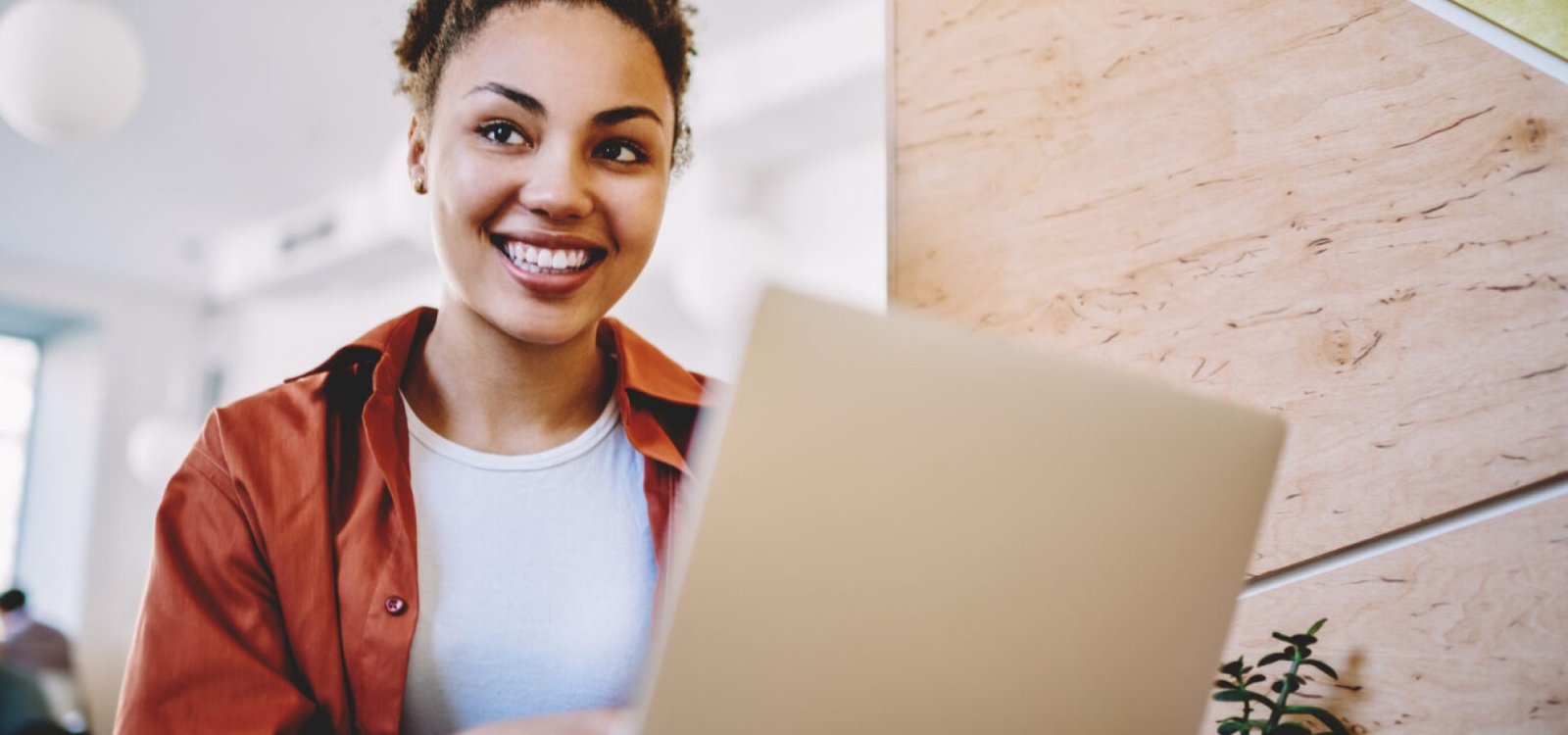Cheerful hipster girl sitting with modern netbook in coworking s