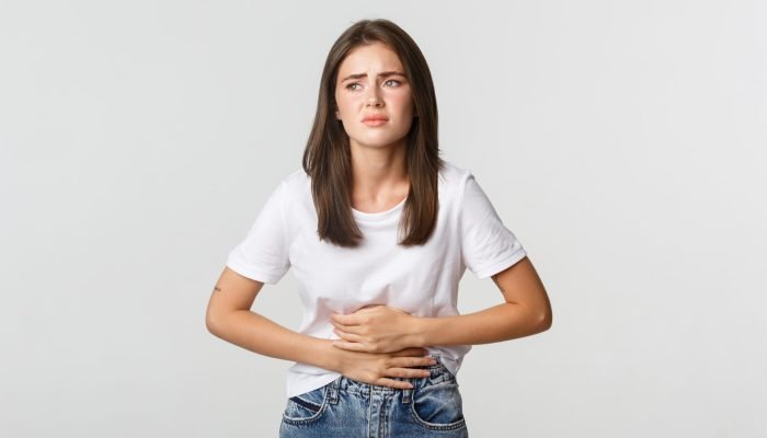 Woman having stomach ache, bending and holding hands on belly, discomfort from menstrual cramps.